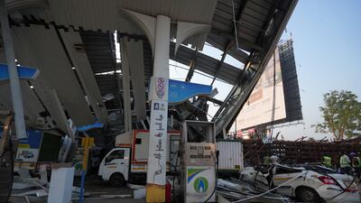 Rescue teams stand next to damaged vehicles at the fuel station. Reuters
