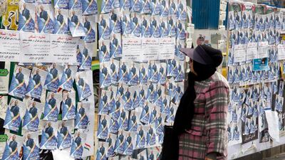 An Iranian woman looks at the electoral posters. AFP