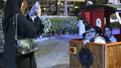 A mother takes photos of her children before they head out on the train ride at the Winter Wonderland event on the Maryah Island waterfront promenade