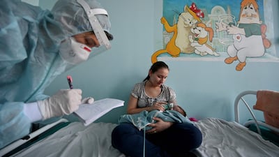 A mother holds an oxygen mask over the face of her baby suffering from Covid-19 in Kiev, Ukraine. AFP