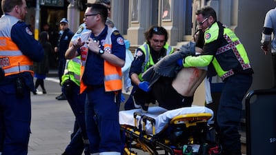 A woman is carried by paramedics, as police officers investigate a scene following reports of a stabbing in Sydney, Australia. REUTERS