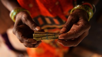 A female labourer shows a bundle of bidis which she rolled.