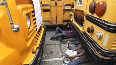 Bus drivers sit underneath a bus during a strike to demand improved security, amid a crime wave against public transport workers, in Tegucigalpa on October 22, 2014. Bus drivers in Tegucigalpa, Honduras parked their vehicles and walked off the job on Wednesday to protest against a crime wave that has seen nearly 40 transport workers killed this year alone. According to local media, the drivers of about 2,000 buses in the capital called on the government to do more to protect them from being extorted by local gangs demanding 'protection money'. Jorge Cabrera / Reuters