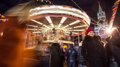 People stand next to a vintage carousel at the Christmas market on the Red Square in Moscow. Natalia Kolesnikova / AFP