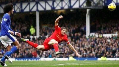 Liverpool's Steven Gerrard, centre, fires a shot goalwards as Everton's Marouane Fellaini watches.