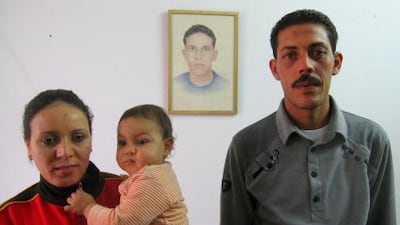 Salem Bouazizi with his wife, Salma Ameri, and their son, Omar, in Sfax, Tunisia. On the wall is a portrait of Salem's late brother, Mohamed Bouazizi.