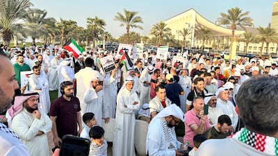 People gather near Kuwait's parliament building holding banners and Palestinian flags in Kuwait City. Reuters