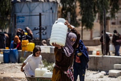 A woman in the Syrian city of Hasaka carries a container of water provided by Unicef after supply from the Allouk station was disrupted in July 2021. AFP