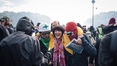 People escort a woman suffering the effects of tear gas on Pont d'Austerlitz. More than 1,000 youths with black jackets and face masks joined the traditional union-led demonstration for worker's rights and attacked police and buildings. AFP/Lucas BARIOULET