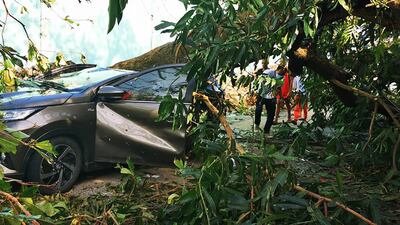 Residents walk past a car damaged by a fallen tree in Surigao City, Surigao del Norte province. AFP