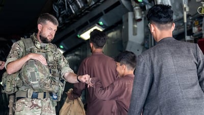 A member of the British military greets a child during evacuation efforts in August 2021 at the Kabul airport in Afghanistan. UK MoD Crown Handout via Reuters