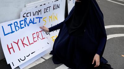 A woman in a niqab collects signs at a demonstration against the Danish face veil ban. Reuters