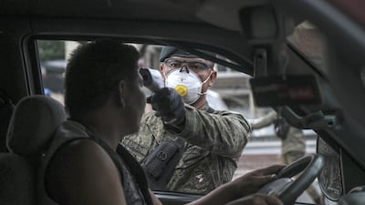 A member of the Philippine Army wearing a protective mask takes the temperature of the driver of a vehicle, traveling into Metro Manila, at a check point on Mindanao Avenue. Bloomberg