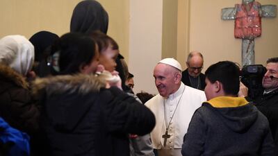 Pope Francis greets the refugees with the cross in the background. EPA