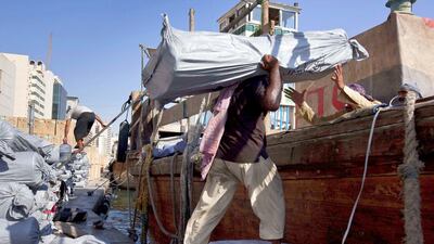 Workers load a wooden cargo dhow bound for Iran from Dubai. (Photo: Antonie Robertson/The National)