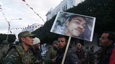 A Tunisian protester holds a placard of a man who died in previous protests, Mohammed Amin, during a demonstration to demand a new government free of officials of the ousted regime of former president Zine el Abidine Ben Ali, near the prime minister's office in Tunis.