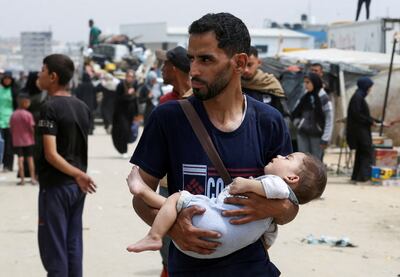 A man carries a child as Palestinians flee Rafah. Reuters