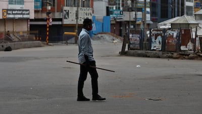 A plainclothes policeman holds a stick to prevent movement of people inside a containment zone during lockdown in Bengaluru, India. India's coronavirus tally is fourth in the world behind the US, Brazil and Russia. AP Photo