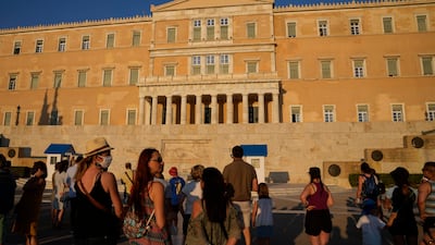 Tourists watch the changing of the Presidential guards ceremony outside the Greek parliament in central Athens.