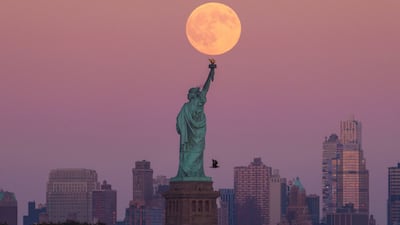 The harvest supermoon rises behind the Statue of Liberty in New York. AP