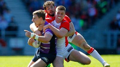 George Williams, left, of Wigan is tackled by Paul Wellens and Joe Greenwood, right, of St Helens during the Super League match in St Helens, England. Paul Thomas / Getty Images