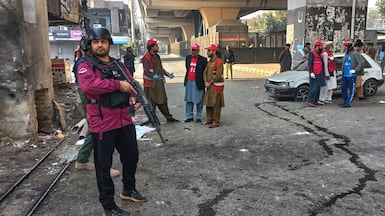 Security officials patrol the site of a suicide bombing at the main gate of paramilitary force headquarter in Peshawar. AP