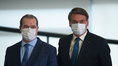 Brazil President Jair Bolsonaro, right, insists on a return to normalcy to prevent economic collapse. Getty Images