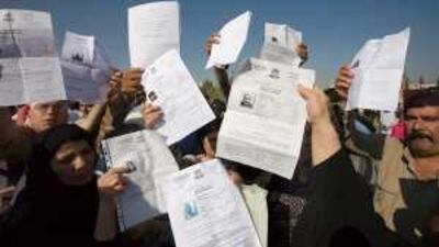 Iraqi refugees hold up their registration certificates during the protest outside the UN refugee agency's office in Damascus.