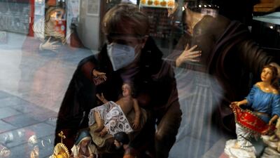 A woman wearing a face mask looks at religious figurines in a shop window, amid the coronavirus disease outbreak in Madrid, Spain. Reuters