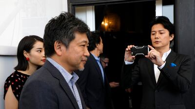 Actor Fukuyama Masaharu, right, films with his phone as director Kore-eda Hirokazu walks in front of him as he arrives for the photo call of the film Sandome No Satsujin (The Third Murder) AP Photo / Domenico Stinellis
