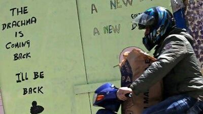 A motorist drives next a graffiti, in central Athens. Greece held crucial elections on June 17. (AP Photo/Petros Giannakouris)