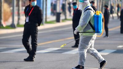 A worker in a protective suit sprays disinfectant on the street during the 2020 Shanghai marathon. AFP