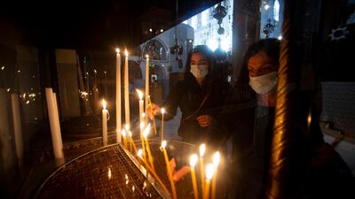 Christian worshippers light candles in the Church of the Nativity, traditionally believed to be the birthplace of Jesus Christ, in the West Bank city of Bethlehem. Normally packed with tourists from around the world at this time of year, Bethlehem resembles a ghost town – with hotels, restaurants and souvenir shops shuttered by the pandemic. Majdi Mohammed / AP Photo