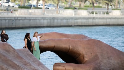 Visitors take photos near the giant sculpture at Yas Bay Waterfront during the Eid Al Fitr holiday in Abu Dhabi. Khushnum Bhandari / The National
