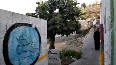 Local residents walk next to a wall painted with graffiti in El Bustan (King's Garden) part of Silwan neighborhood in east Jerusalem on Monday, June 21, 2010.
