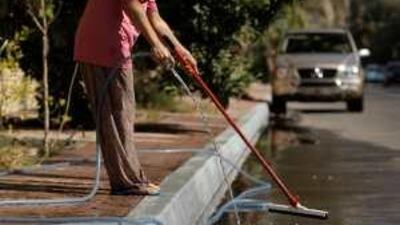 A housekeeper waters the plants and washes the pavements in Abu Dhabi.
