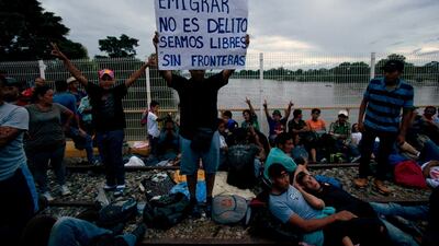 A migrant bound for the US-Mexico border holds up a sign with a message that reads in Spanish: "To emigrate is not a crime, let's be free, without borders". Moises Castillo / AP