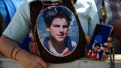 A woman holds a bag and a phone in a case with images depicting Carlo Acutis, a British-born Italian boy who will become the first millennial to be made a Catholic saint in a ceremony in St Peter's Square at the Vatican. Reuters