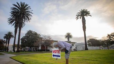 Lorraine Crawford puts vote signs as the sun rises the Main Street Branch Library vote centre in Huntington Beach, California. AFP