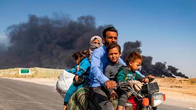 Displaced people, fleeing from the countryside of the Syrian Kurdish town of Ras al-Ain along the border with Turkey, ride a motorcycle together along a road on the outskirts of the nearby town of Tal Tamr on October 16, 2019. AFP