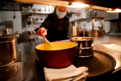A cooker wears a protective face mask prepare a fondue. AFP