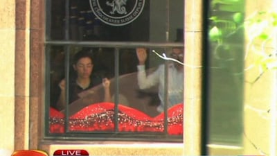 This image taken from video shows people holding up their hands inside the cafe in Sydney, Australia on Monday. A gunman took an unknown number of people hostage inside the downtown Sydney chocolate shop and cafe at the height of Monday morning rush hour, with two people inside the cafe seen holding up a flag believed to contain an Islamic declaration of faith. AP Photo / Channel 7 via AP Video