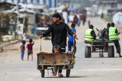 A Palestinian man pushes a child in a cart at Bureij refugee camp in Gaza. AFP