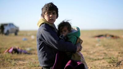 A boy holds a baby near the village of Baghouz, Deir Ezzor province, Syria, March 1, 2019. REUTERS