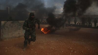 Fighters of Jaysh al-Izza, a formerly US-backed Syrian rebel group active in northern Hama province and parts of Idlib, runs through smoke during a military display. AFP