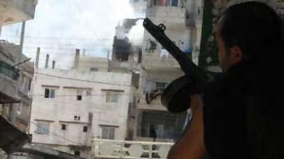 Smoke billows from the Jabal Mohsen neighbourhood while a Sunni Muslim gunman takes cover behind a wall in the Bab al-Tebbaneh district during clashes in between opponent factions the northern Lebanese city of Tripoli.