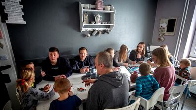 Katja, her husband and their 11 children sit around a table in their home. AP Photo