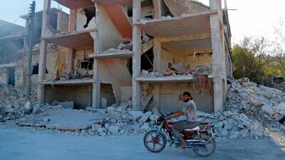 A Syrian man rides a motorcycle past a destroyed building in Jisr al-Shughur, in Idlib, on September 4, 2018. AFP