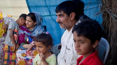 Yaqoub Al Balooshi sits under an awning with his step-granddaughter Shaikha Khalid Al Baloosh, 4, and his grandson Abdullah Khalil Ibrahim, 8. In the background, Shihab Khalid Shihab nuzzles up to his mother Zahra Al Balooshi. This extended family, originally from Dubai, have been camping by the Dibba beach every holiday since 2009.