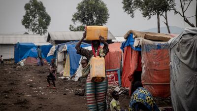 A displaced woman carries two jerry cans of water to supply her shelter at the Kayembe camp near Goma, Democratic Republic of Congo. AFP
